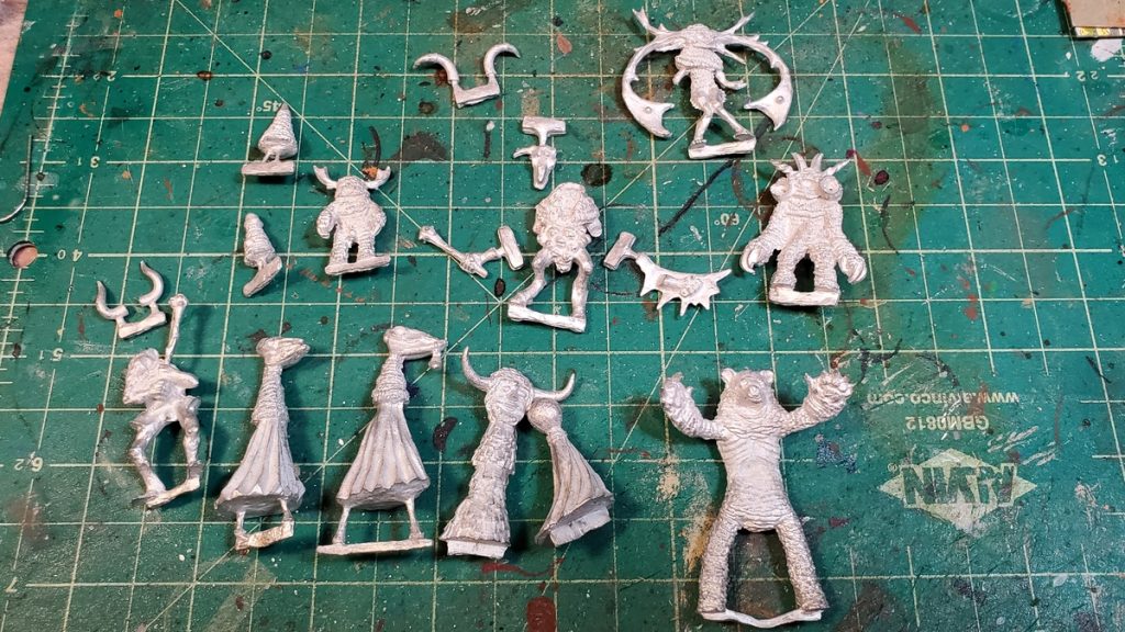 the twelve miniatures all in actual pewter, laid out on a cutting mat for scale.